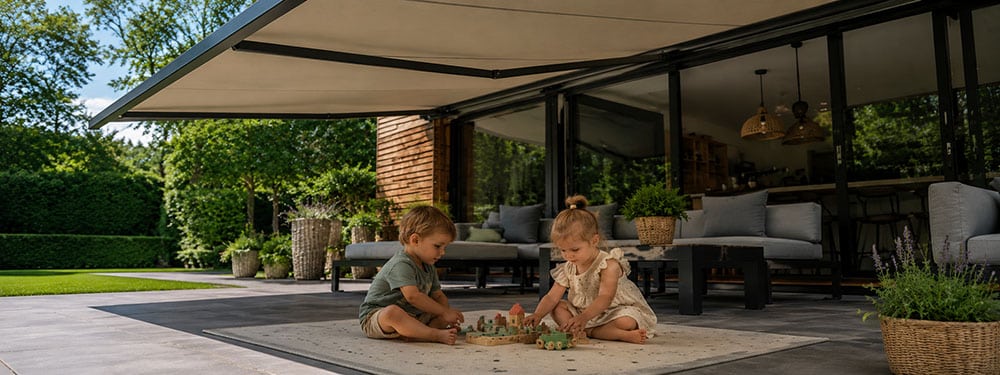 schaduw-tuin-kinderen-beschermen-germa-zonwering Kinderen spelen in schaduw, beschermt van UV-straling, dankzij zonnescherm.